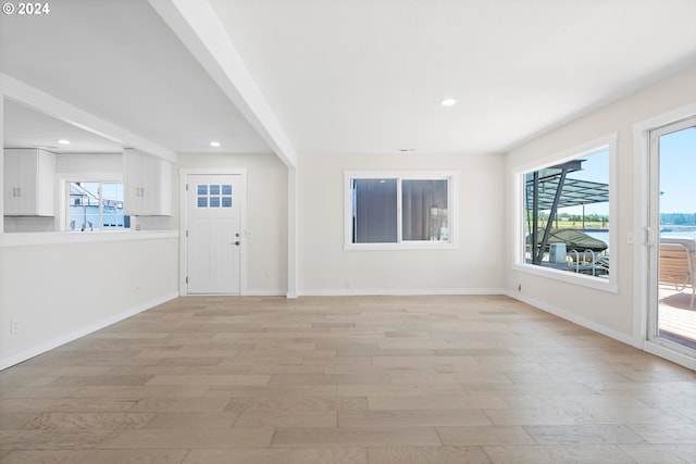 unfurnished living room featuring a wealth of natural light and light hardwood / wood-style flooring