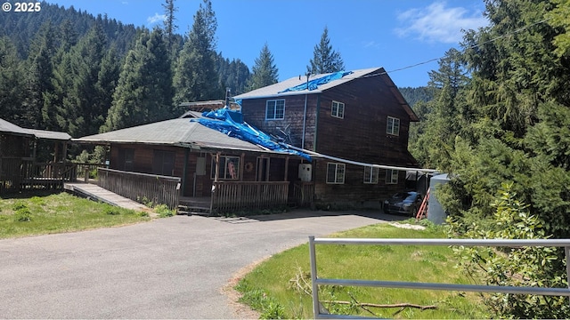 2999 Speaker Rd, Wolf Creek, OR 97497 - view of front of property with aphalt driveway, a porch, and a view of trees