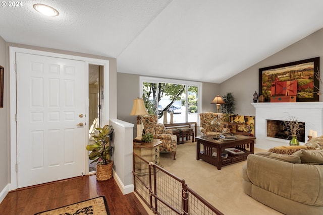 living room with a fireplace, hardwood / wood-style floors, a textured ceiling, and vaulted ceiling