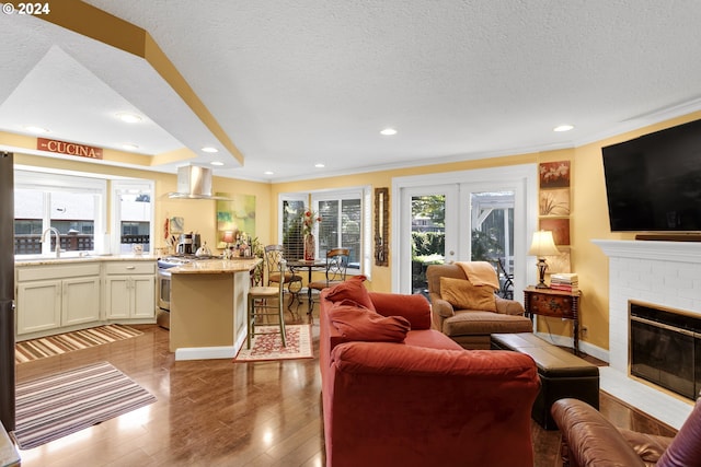 living room with light wood-type flooring, a brick fireplace, a textured ceiling, and sink