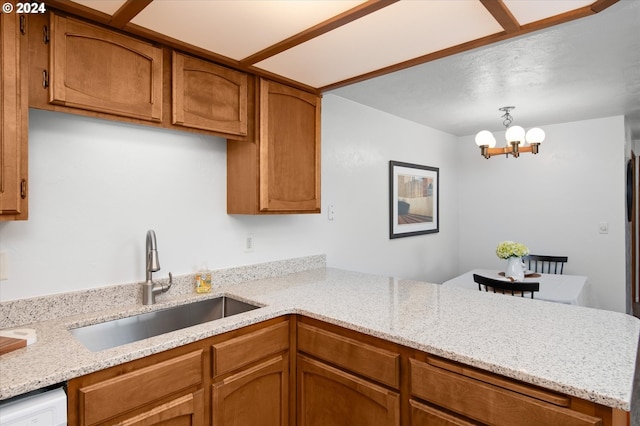 kitchen with white dishwasher, kitchen peninsula, a notable chandelier, sink, and pendant lighting