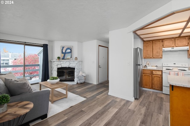 kitchen featuring a premium fireplace, hardwood / wood-style floors, white electric range, and stainless steel fridge