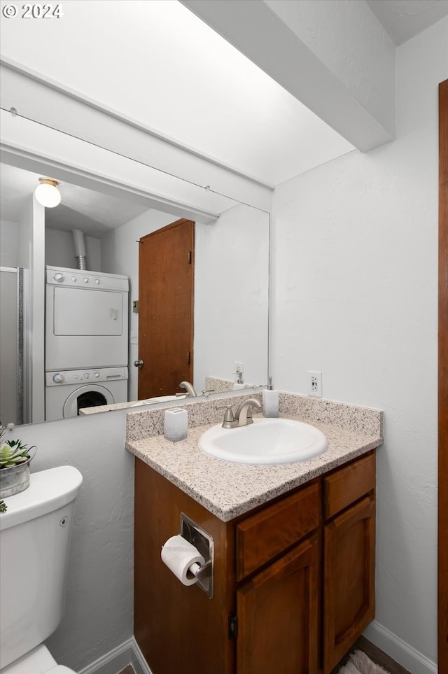 bathroom featuring toilet, stacked washer and clothes dryer, and vanity