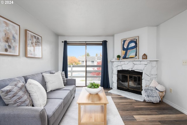 living room featuring wood-type flooring and a stone fireplace