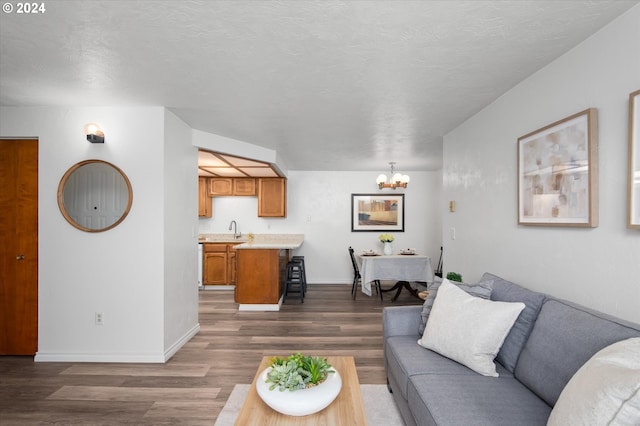 living room with sink, a notable chandelier, dark hardwood / wood-style floors, and a textured ceiling