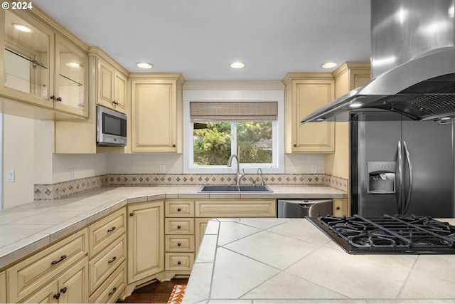 kitchen featuring exhaust hood, light brown cabinetry, sink, stainless steel appliances, and tile countertops