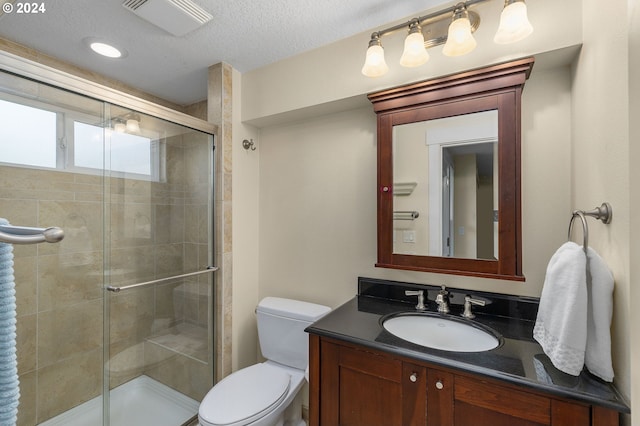 bathroom featuring a textured ceiling, toilet, walk in shower, and vanity