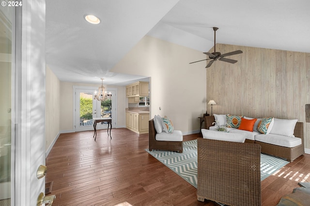 living room featuring wood walls, dark hardwood / wood-style flooring, lofted ceiling, and ceiling fan with notable chandelier