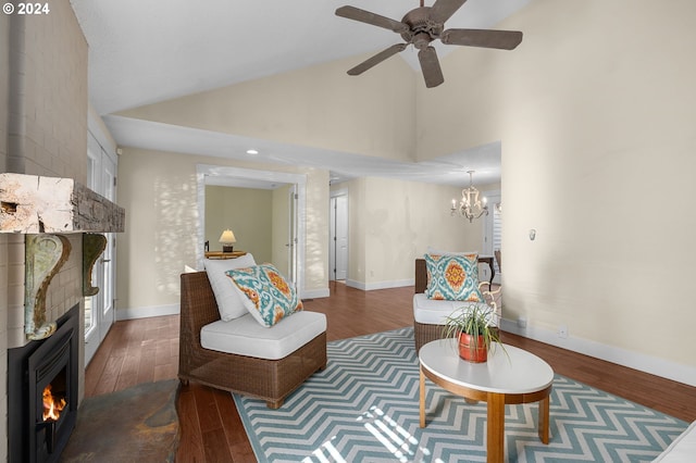 living room featuring high vaulted ceiling, a large fireplace, dark hardwood / wood-style flooring, and ceiling fan with notable chandelier