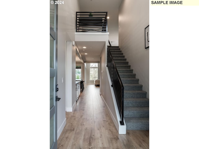 foyer entrance featuring a towering ceiling and light wood-type flooring