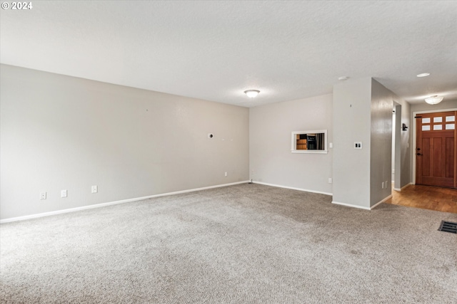 unfurnished living room with light colored carpet and a textured ceiling