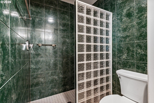 bathroom with a tile shower, toilet, and tile walls