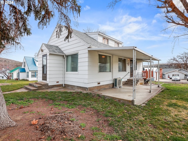 rear view of property featuring central AC unit, a yard, and covered porch