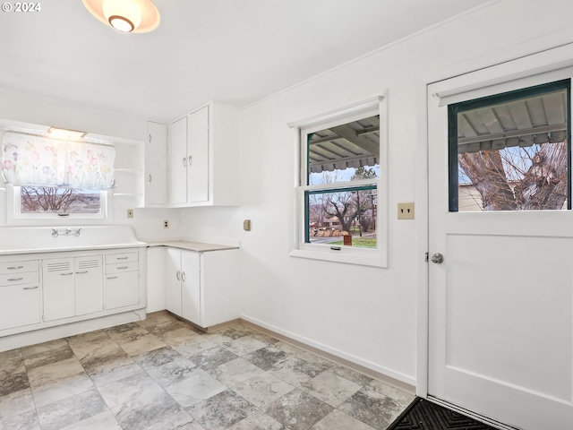 kitchen featuring sink, light tile flooring, white cabinets, and a wealth of natural light