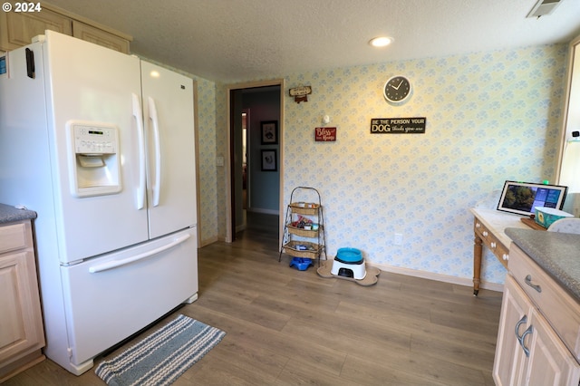 kitchen with hardwood / wood-style floors, a textured ceiling, white fridge with ice dispenser, and light brown cabinetry