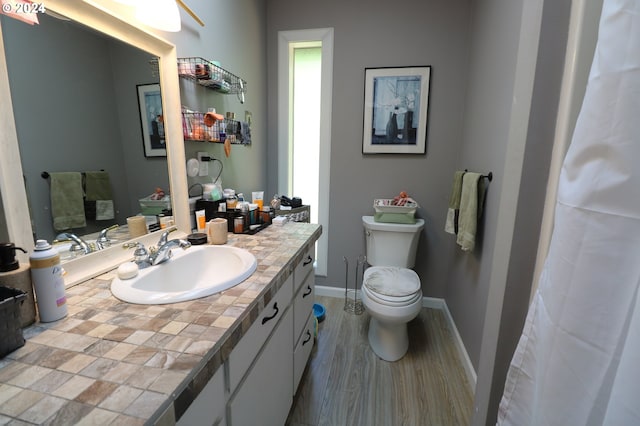 bathroom with wood-type flooring, vanity, and toilet