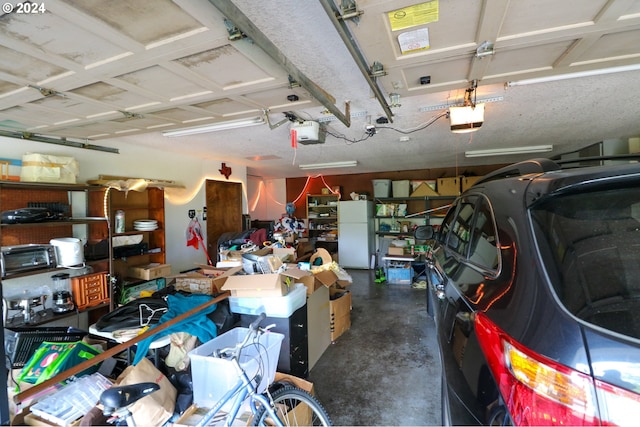 garage featuring white fridge and a garage door opener