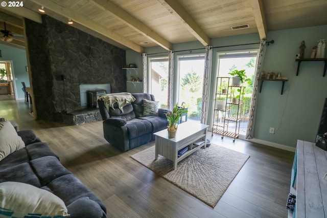 living room with vaulted ceiling with beams, light hardwood / wood-style floors, a stone fireplace, and ceiling fan