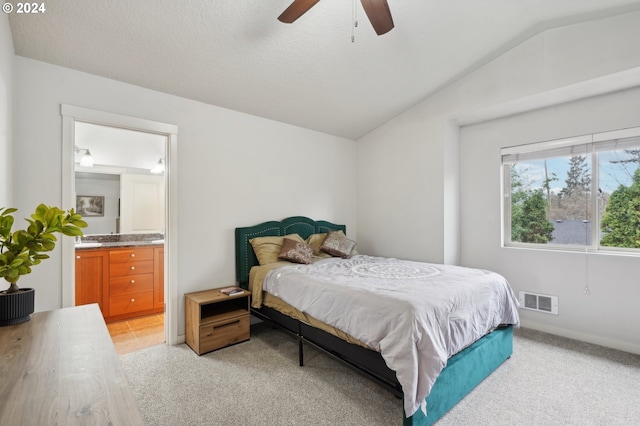 carpeted bedroom with ensuite bathroom, ceiling fan, a textured ceiling, and vaulted ceiling