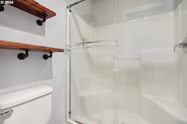 bathroom featuring toilet and a shower with door