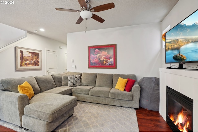 living room featuring a tile fireplace, ceiling fan, a textured ceiling, and hardwood / wood-style flooring