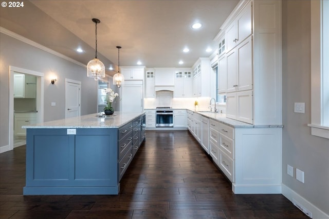 kitchen featuring sink, white cabinets, oven, and decorative light fixtures