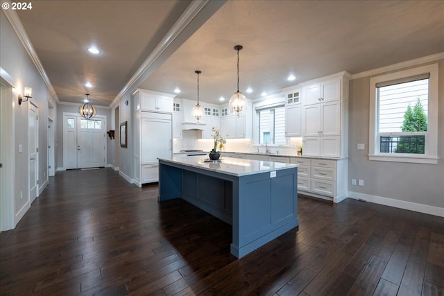 kitchen with light stone countertops, dark hardwood / wood-style flooring, pendant lighting, white cabinets, and a kitchen island