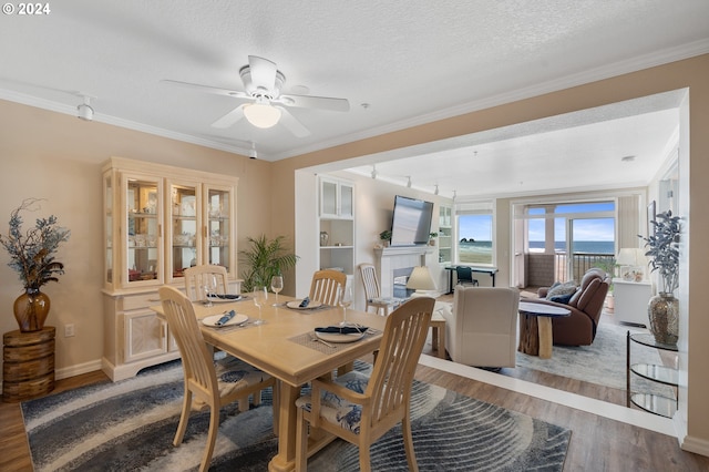 dining room with ceiling fan, hardwood / wood-style floors, a textured ceiling, and ornamental molding