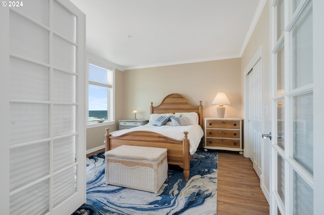 bedroom featuring wood-type flooring, french doors, a closet, and ornamental molding