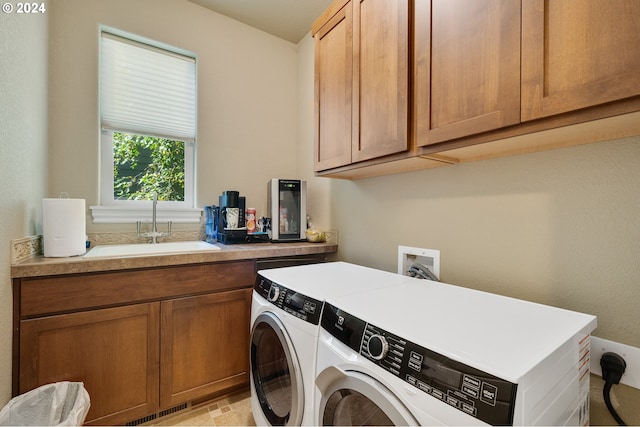 clothes washing area featuring separate washer and dryer, sink, and cabinets