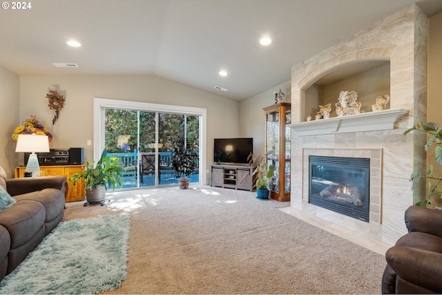 living room featuring a tile fireplace, vaulted ceiling, a healthy amount of sunlight, and light colored carpet