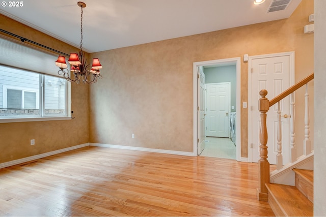 spare room with washer and dryer, a chandelier, and light wood-type flooring