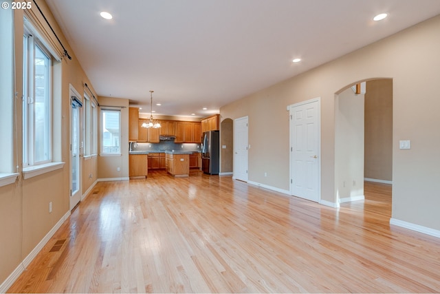 kitchen featuring an inviting chandelier, decorative light fixtures, a center island, light hardwood / wood-style flooring, and stainless steel refrigerator