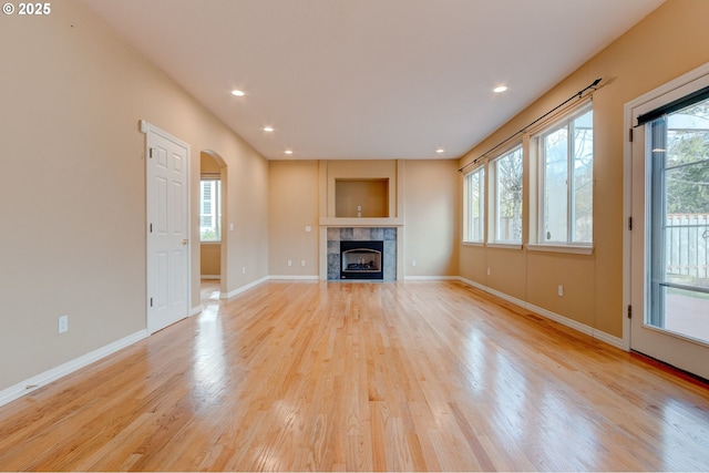 unfurnished living room featuring a healthy amount of sunlight, a fireplace, and light hardwood / wood-style flooring