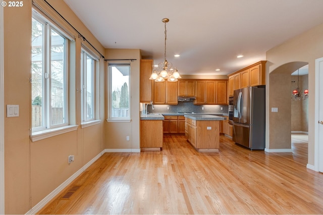 kitchen with a center island, pendant lighting, light hardwood / wood-style floors, and stainless steel fridge with ice dispenser