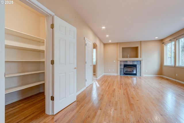 unfurnished living room featuring light hardwood / wood-style flooring and a tile fireplace