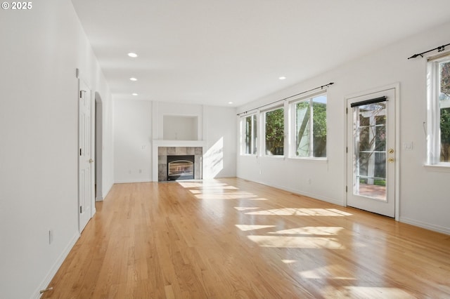 5306 NW Skycrest Pkwy, Portland, OR 97229 - unfurnished living room featuring plenty of natural light, a tiled fireplace, baseboards, and light wood-style flooring