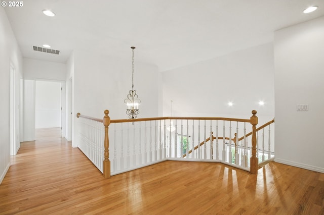 5306 NW Skycrest Pkwy, Portland, OR 97229 - hallway with baseboards, visible vents, an inviting chandelier, an upstairs landing, and wood finished floors