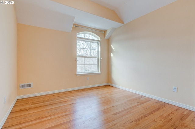 empty room featuring vaulted ceiling and light hardwood / wood-style floors