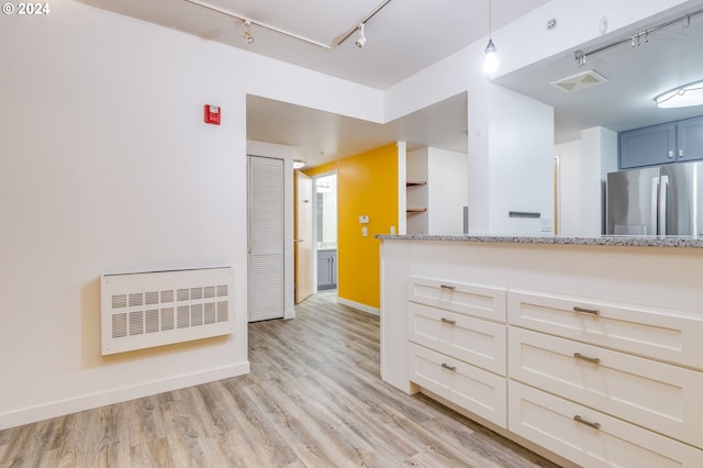 kitchen with light hardwood / wood-style floors, decorative light fixtures, rail lighting, stainless steel refrigerator, and light stone counters