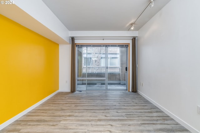 spare room with light hardwood / wood-style flooring and track lighting