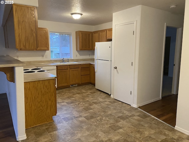 kitchen with a textured ceiling, white fridge, and sink