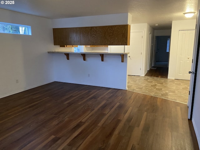 kitchen featuring a breakfast bar, a textured ceiling, kitchen peninsula, and dark hardwood / wood-style floors