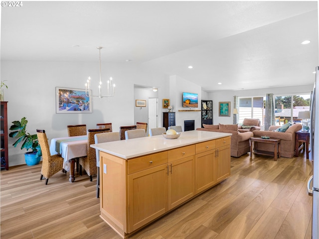 kitchen with a center island, vaulted ceiling, a notable chandelier, and light hardwood / wood-style flooring