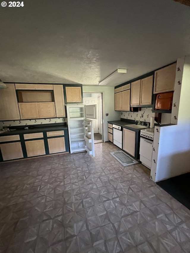 kitchen with white appliances, dark countertops, light floors, open shelves, and a sink