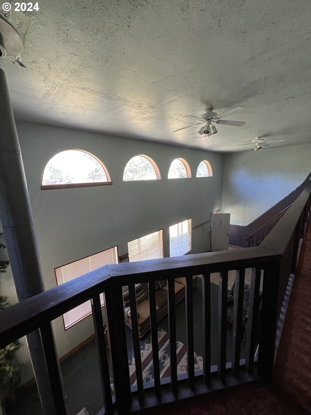 stairway with ceiling fan and a textured ceiling