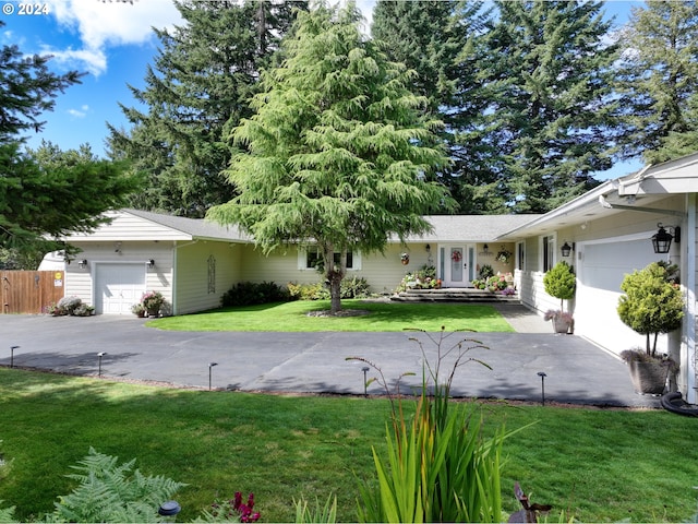 view of front facade featuring a front lawn, an attached garage, fence, and aphalt driveway