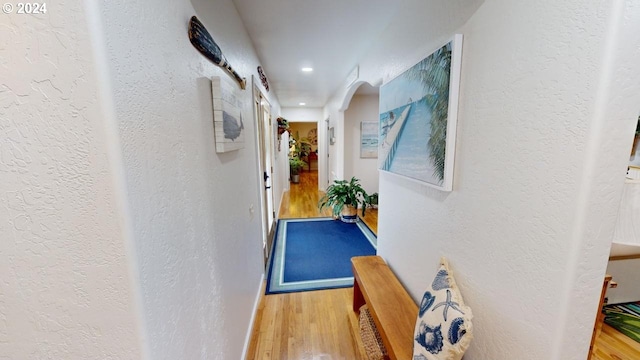 hallway with wood finished floors and a textured wall