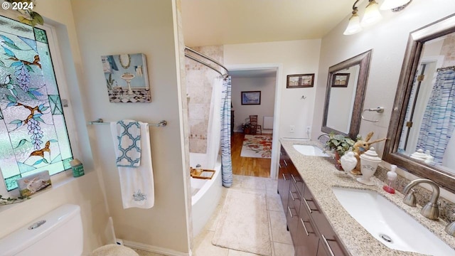 bathroom with double vanity, toilet, shower / tub combo with curtain, and a sink