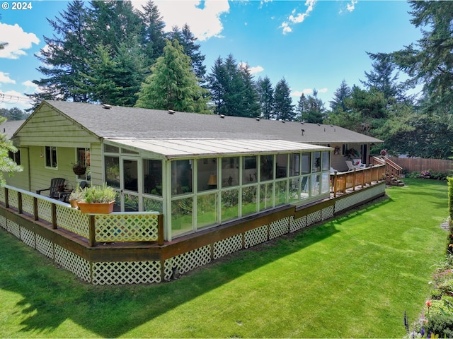 rear view of house featuring a yard, a sunroom, and a deck